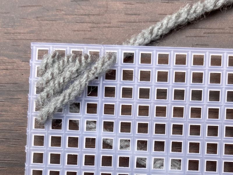 weaving silver colored yarn in plastic canvas