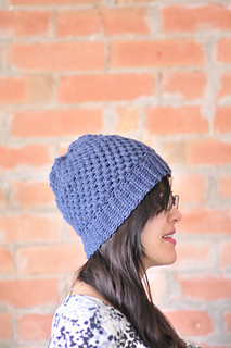 woman wearing a crochet puff stitch hat in front of brick wall