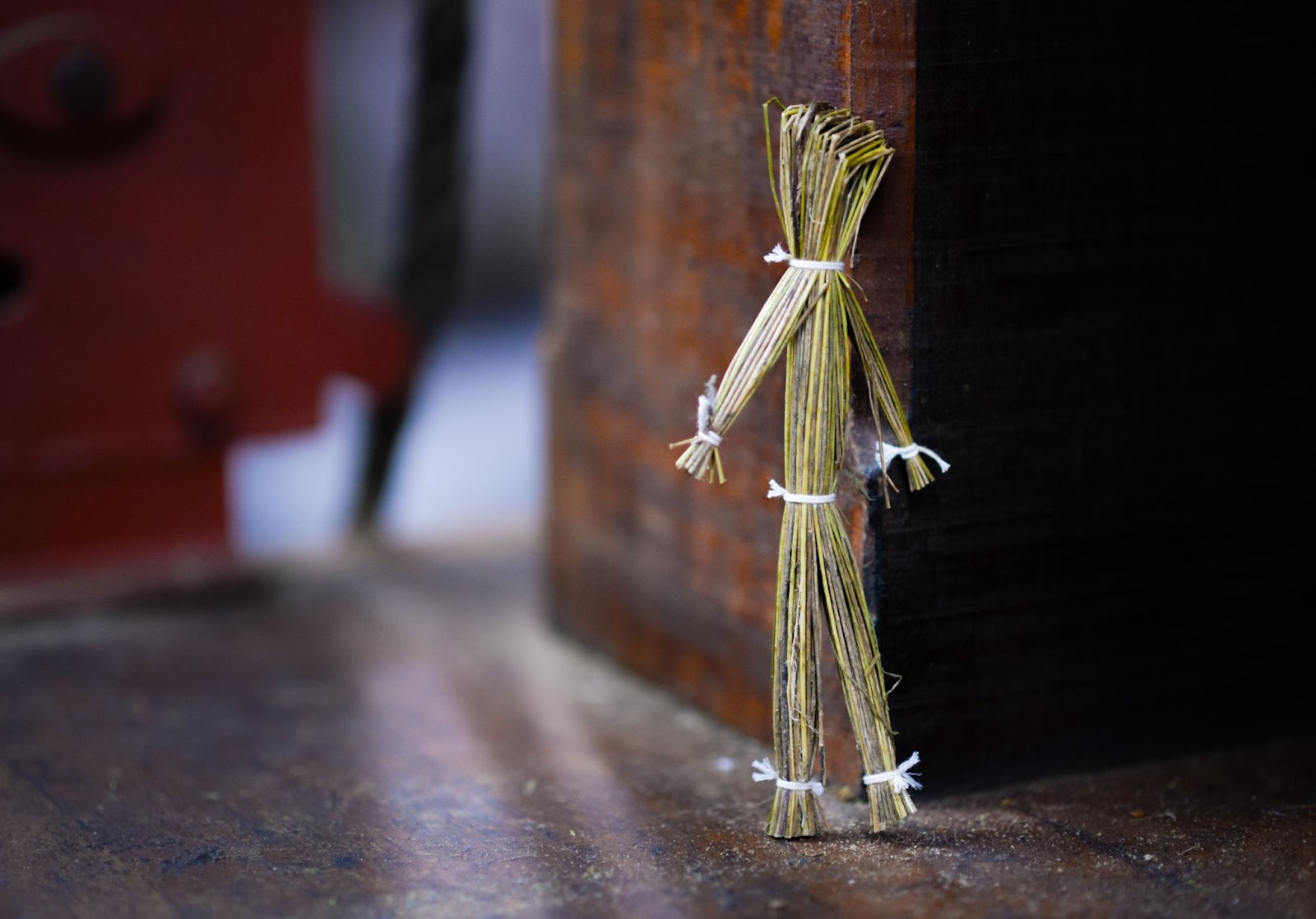 Une figurine d'apparence fragile faite de paille, attachée par une ficelle.