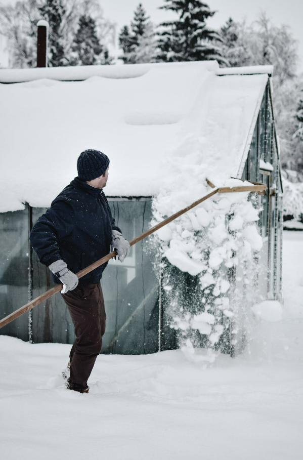 A Man Removing Snow on a Roof