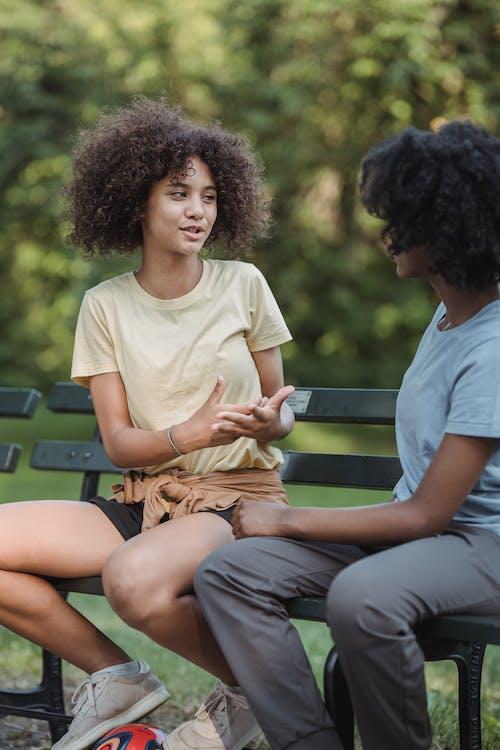 Free Teenage Girls Sitting on the Bench and Chatting Stock Photo