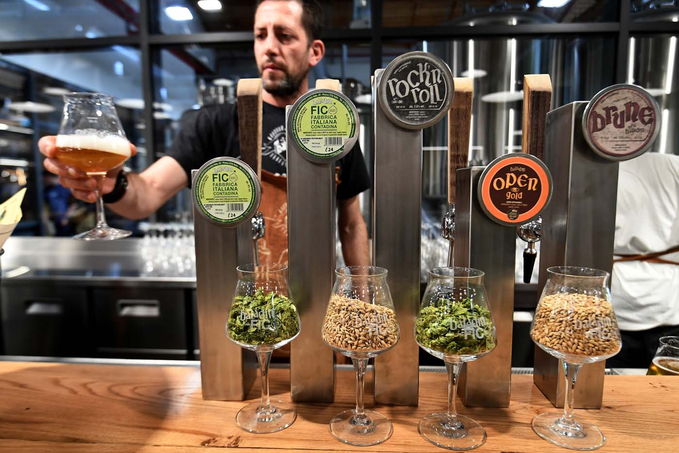 A man offers a glass of artisanal beer at a stand during a press tour at FICO Eataly World agri-food park in Bologna on November 9, 2017.  FICO Eataly World, said to be the world's biggest agri-food park, will open to the public on November 15, 2017. The free entry park, widely described as the Disney World of Italian food, is ten hectares big and will enshrine all the Italian food biodiversity.  / AFP PHOTO / Vincenzo PINTO