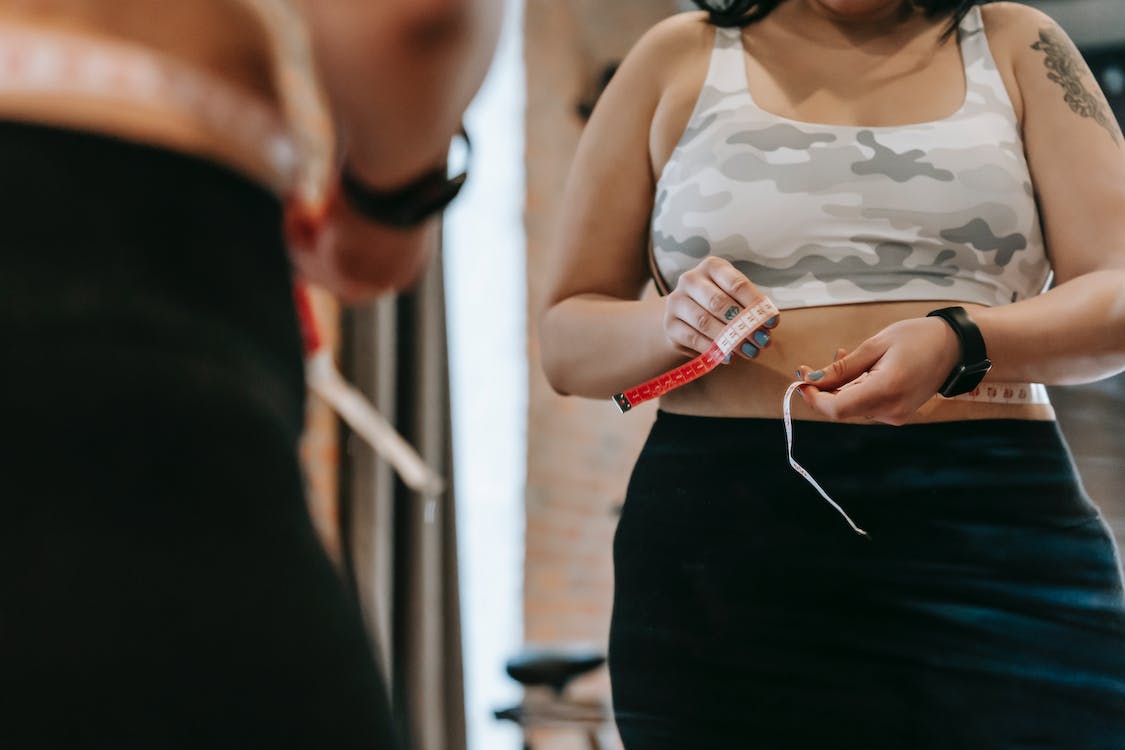Free Woman measuring waist with tape in gym Stock Photo