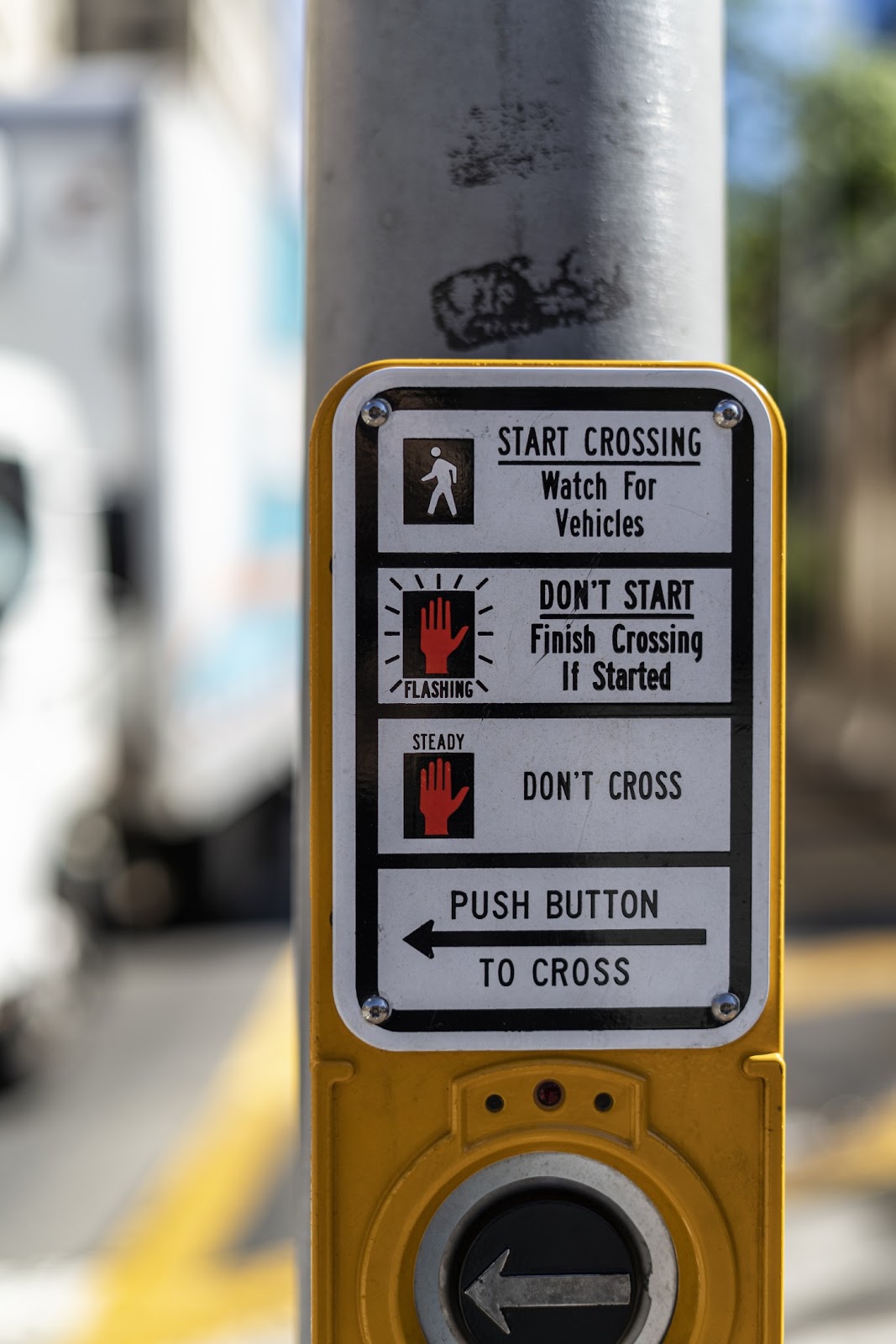 An overly complex crosswalk sign with lots of text and icons.
