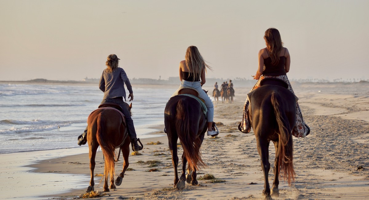 Three girls horseback riding on the beach in Tamarindo which is a fun kid-friendly activity to do on a family vacation