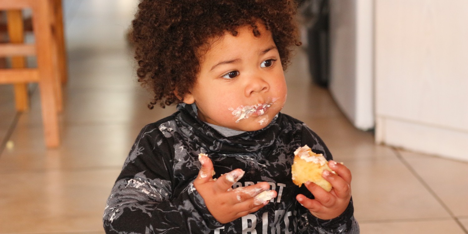 young mixed-race boy eating a cake to feed his chemical engine—a test of sustainability and energy 