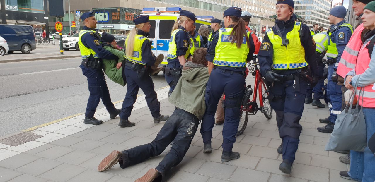 Police drag a protestor along the pavement while another is carried away by two police