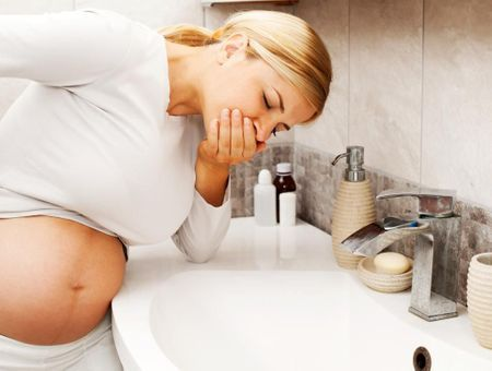 Femme enceinte se tenant au-dessus d'un évier, incommodée par des remontées acides