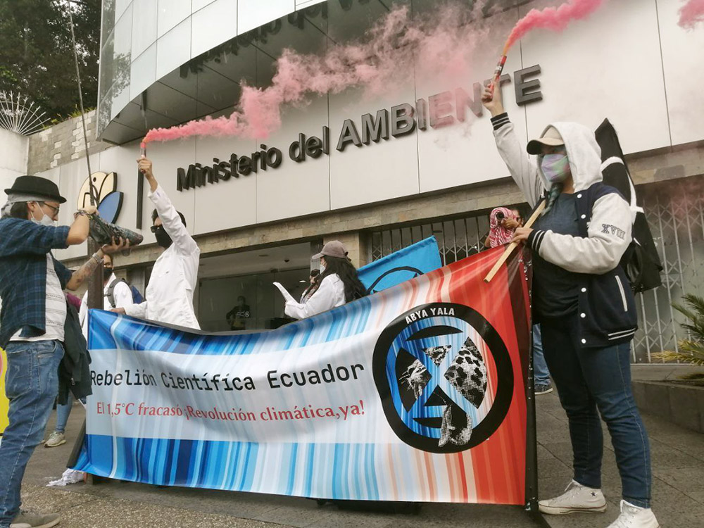Ecuadorian scientists hold a Scientist Rebellion banner and let off red smoke outside the ministry