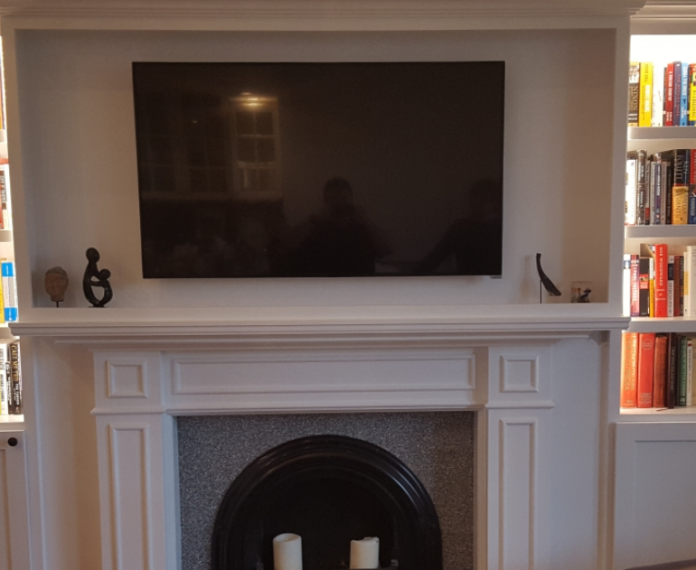 A TV above a fireplace with a white mantle.