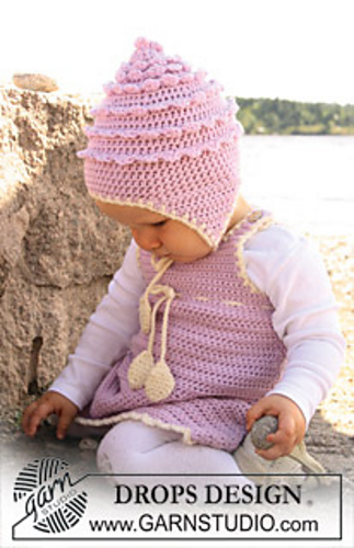 baby playing in the sand wearing a crocheted dress and hat