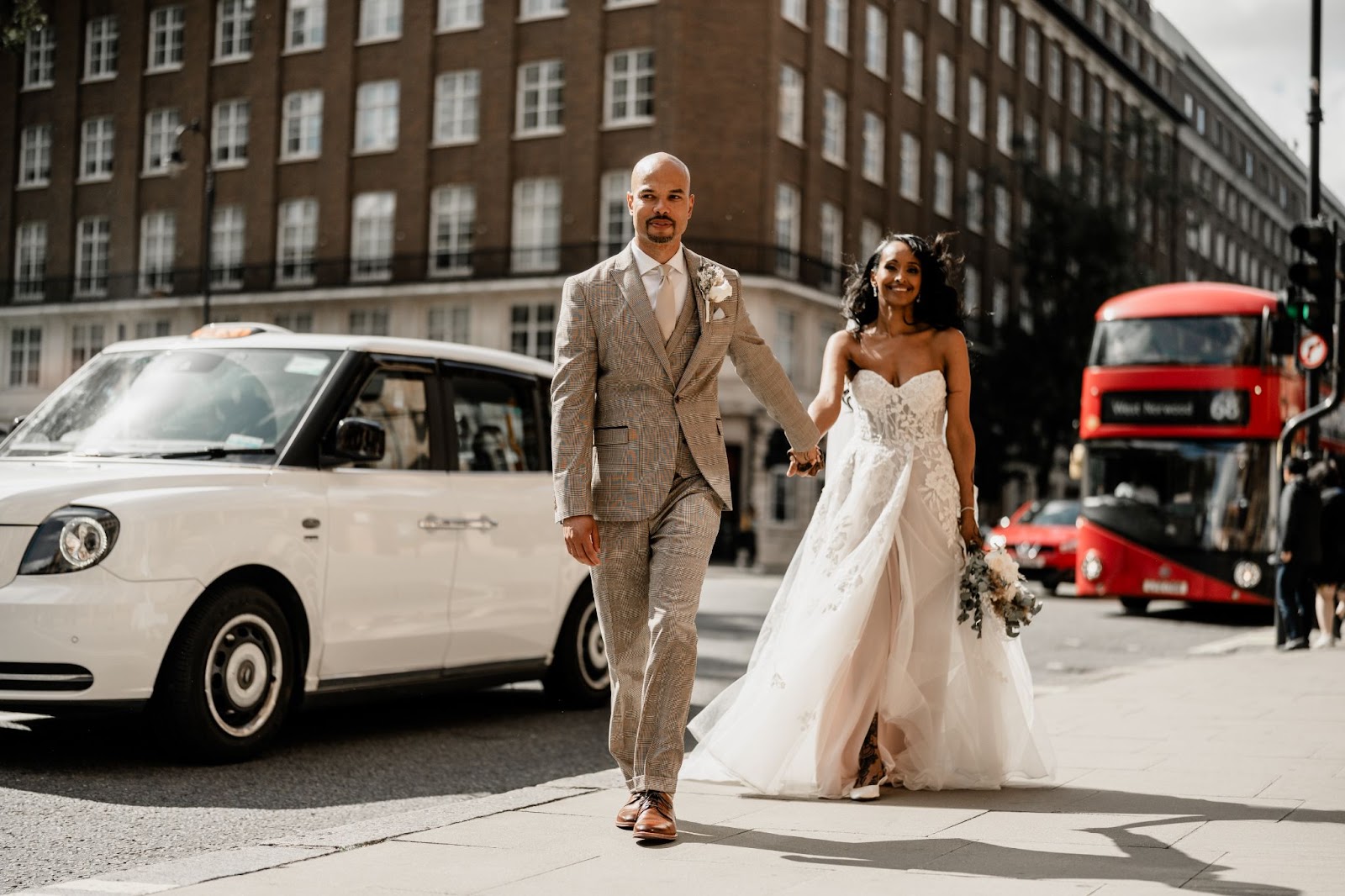Groom leading bride down street of London, red bus in the background
