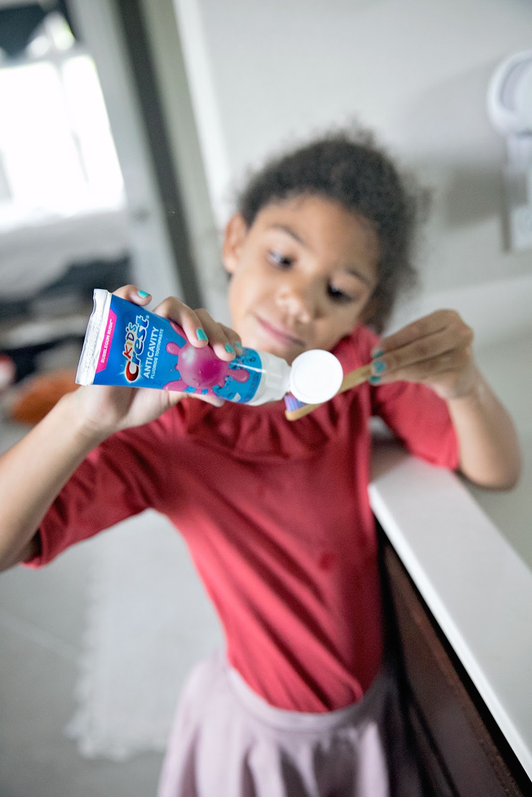 This is our mission to find the best kids toothpaste. Little girl adding bubble gum flavored kids toothpaste to her toothbrush. 