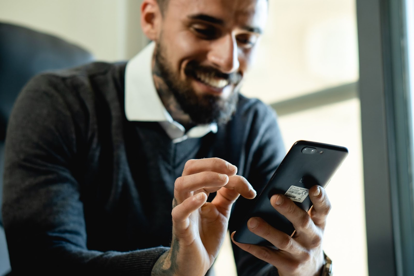 Man smiles while using a smartphone Best Coding Apps for Beginners