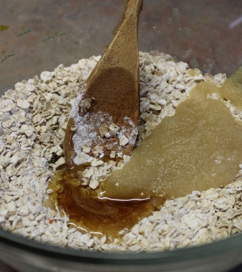 Flour, Oats, Honey, and Applesauce in a glass bowl with a wooden spoon | How to Make Simple Homemade Horse Treats | Mama on the Homestead