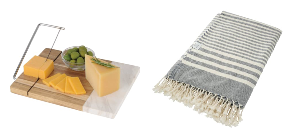 A bamboo and marble cheese cutting board with a piece of cheese and olives on it and a fleece striped blanket.