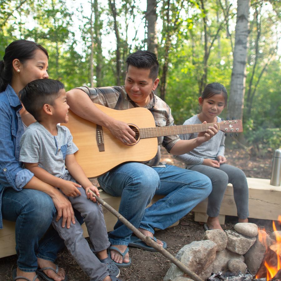 Family playing music around the campfire.