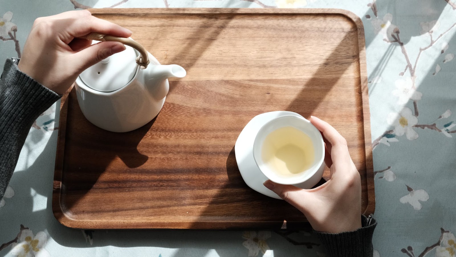 A pot of tea about to be poured into a white cup.