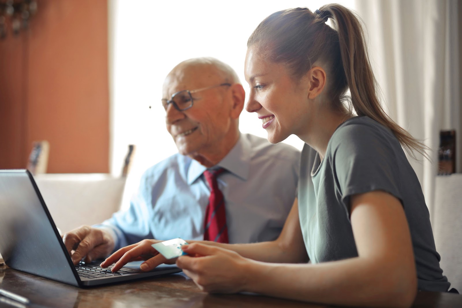 senior man sitting with younger woman on computer