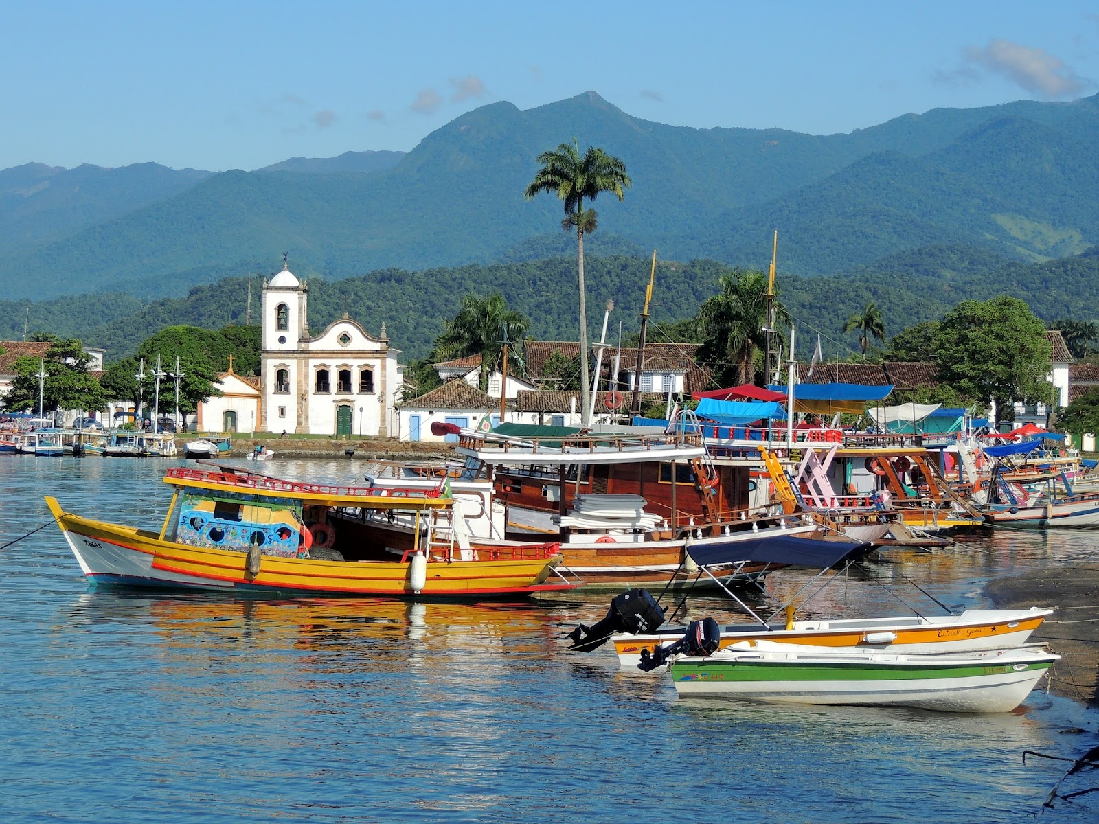 Capitais da Cachaça: barcos coloridos ancorados, ao fundo Igreja de Santa Rita. Paraty uma das cidades com mais marcas de cachaça