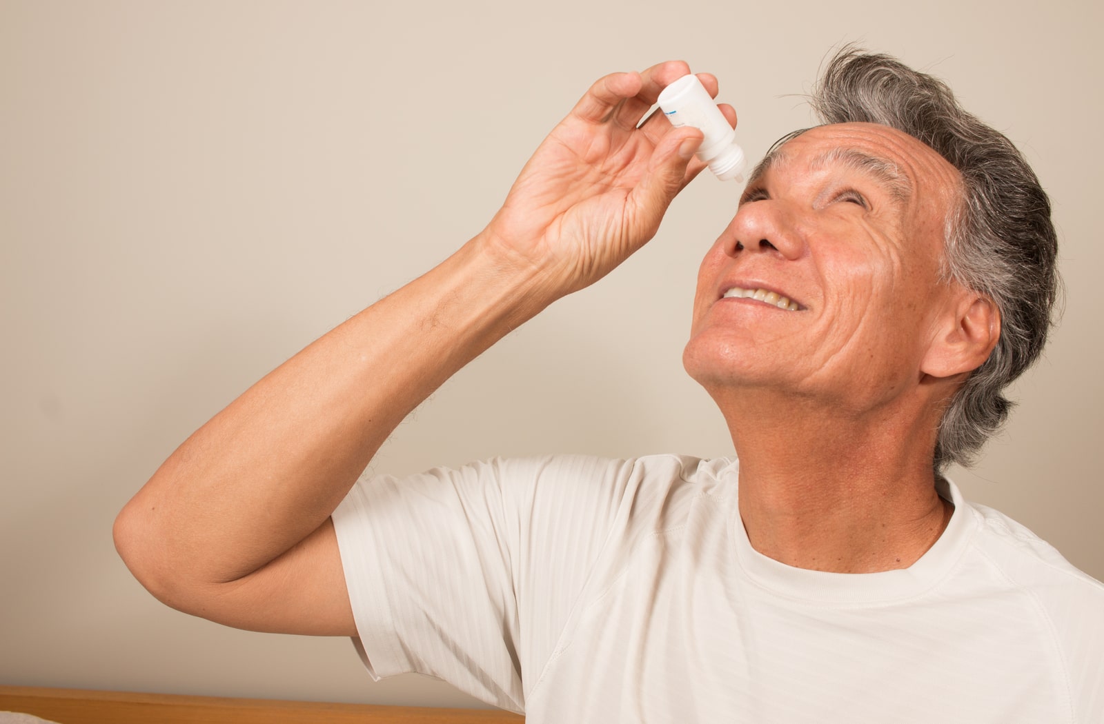 A man putting eye drops in his right eye