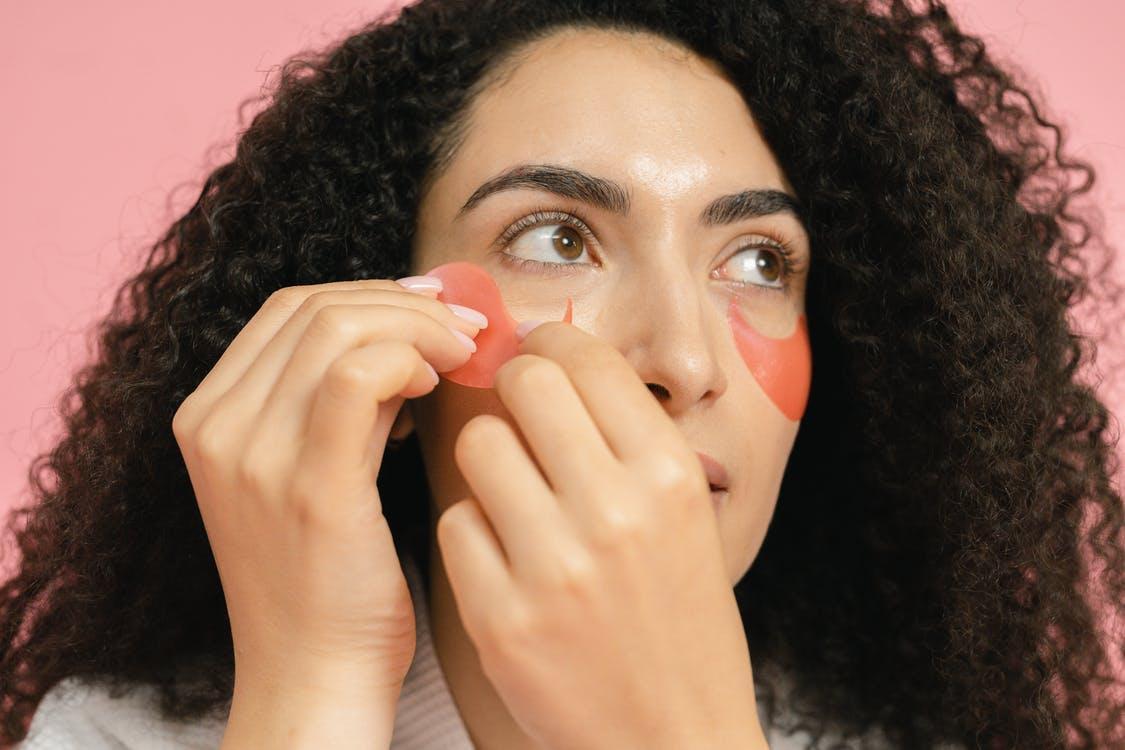 Woman putting on red cosmetic pads under her eyes