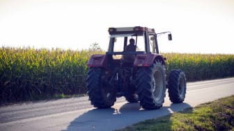 farmer riding tractor alongside fields