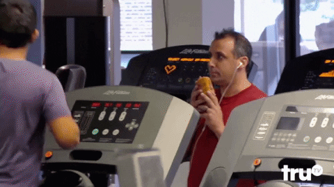 A man eats a sandwhich in a gym