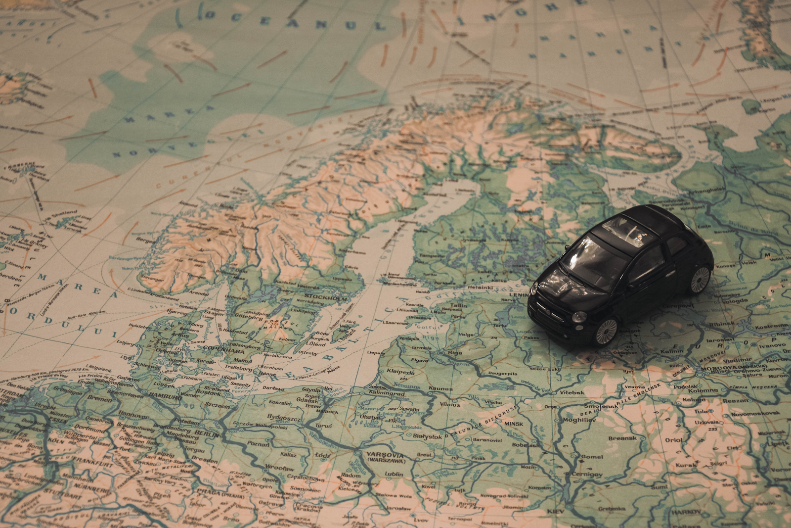 Black toy car on top of a map of Europe.