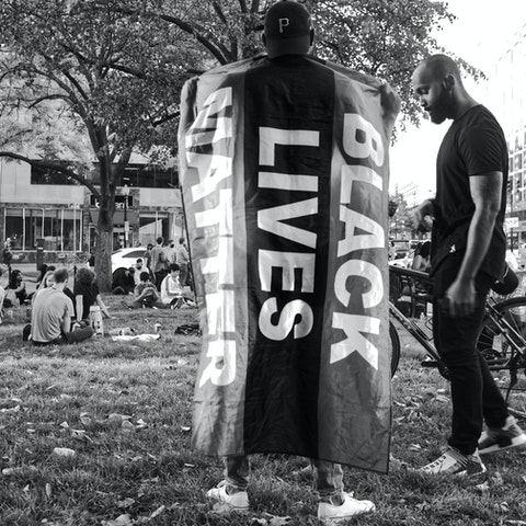 dos hombres sosteniendo una bandera que dice “Black Lives Matter”