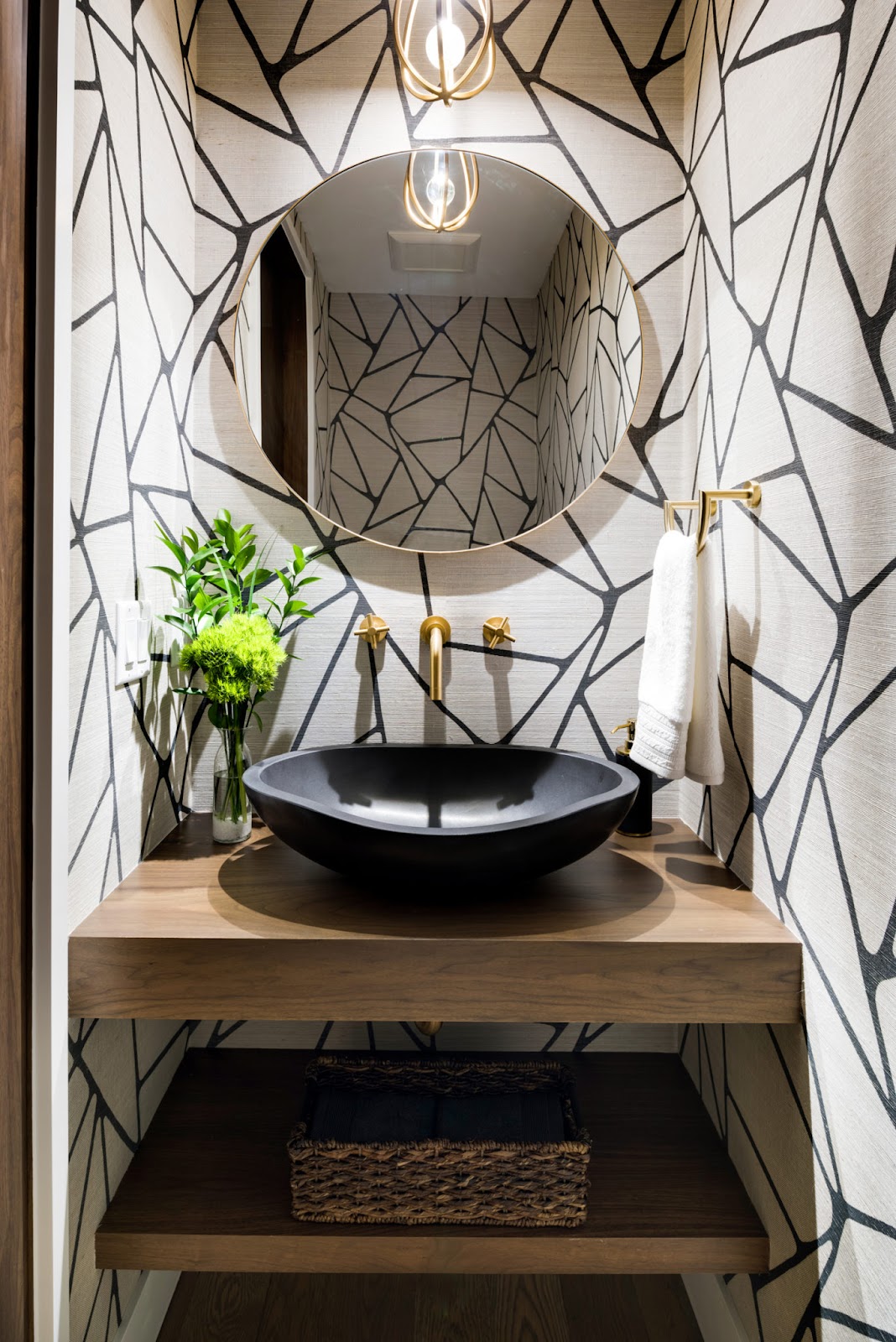 A bathroom with a geometrical black line pattern on white walls and a stone sink