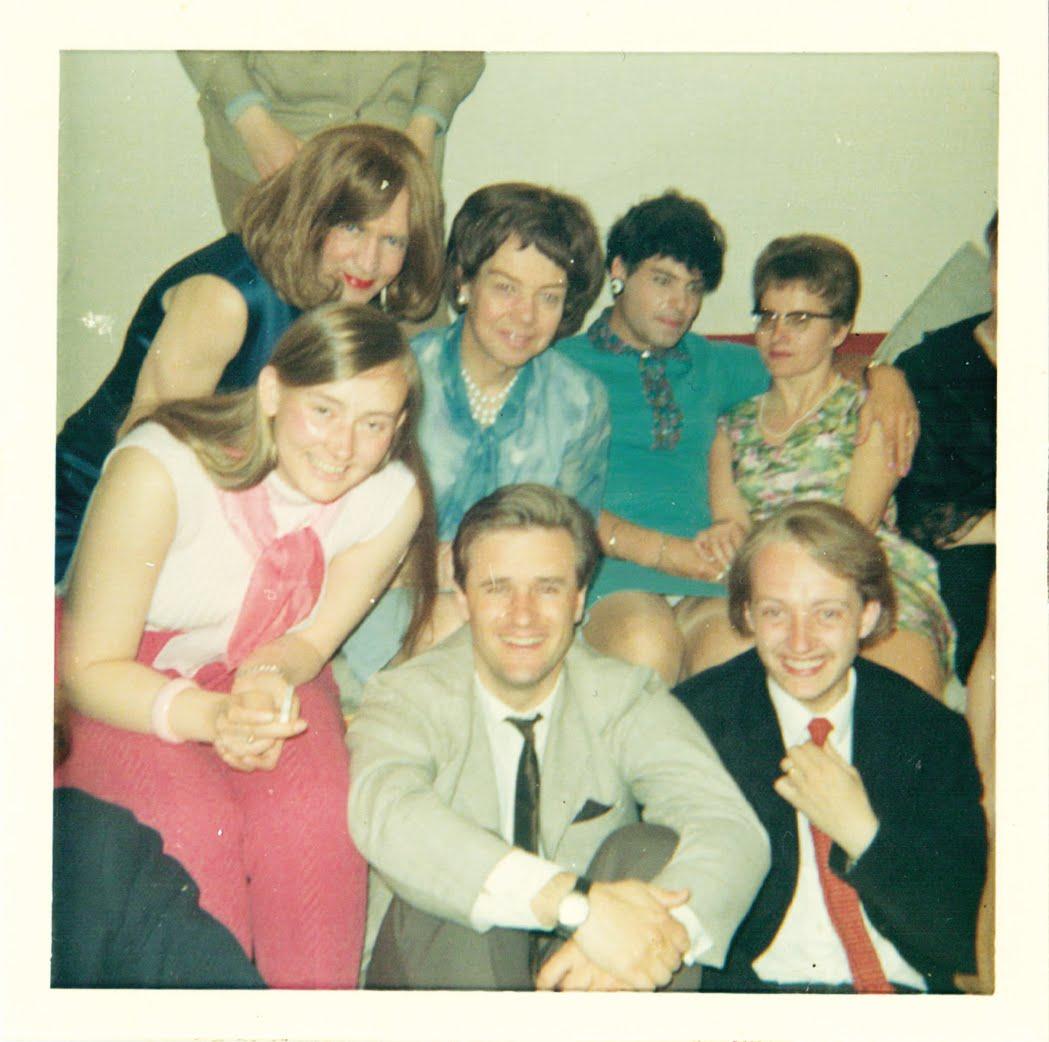 en grupp festklädda människor som ler mot kameran. fotot ser gammalt ut.
