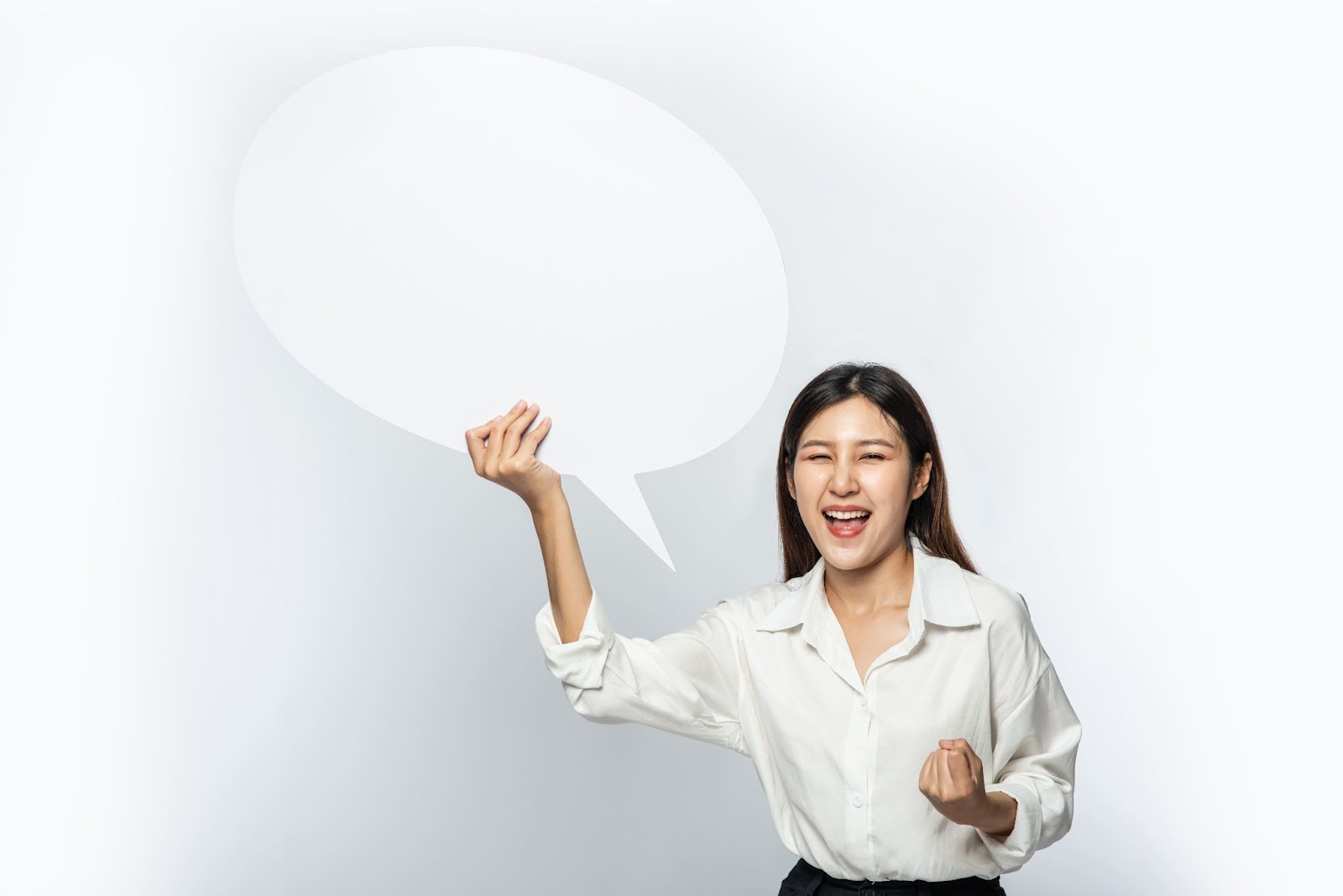 an Asian brown hair woman in a white long sleeve shirt holding a white cutout speech bubble on white background
