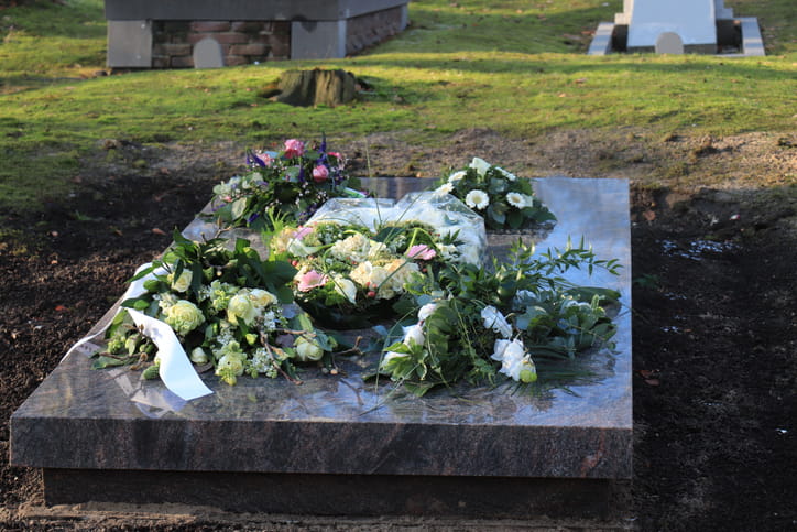 Sympathy flowers with satin ribbons on a grave.