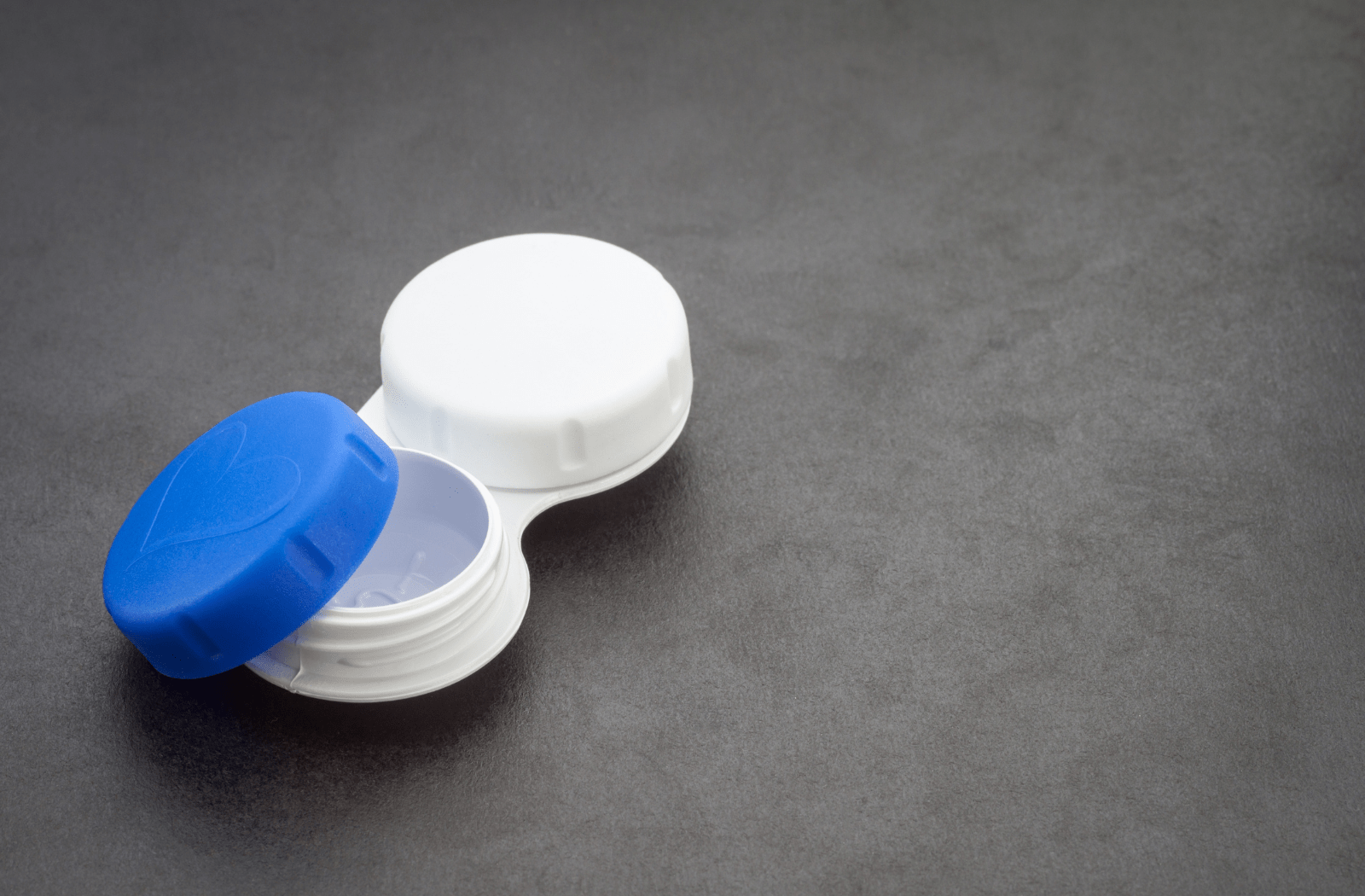A pair of contact lenses sitting inside of a contact lens case that's white and blue