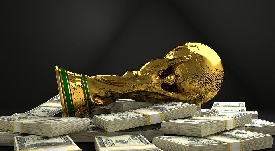 A gold FIFA World Cup trophy lying on a pile of money