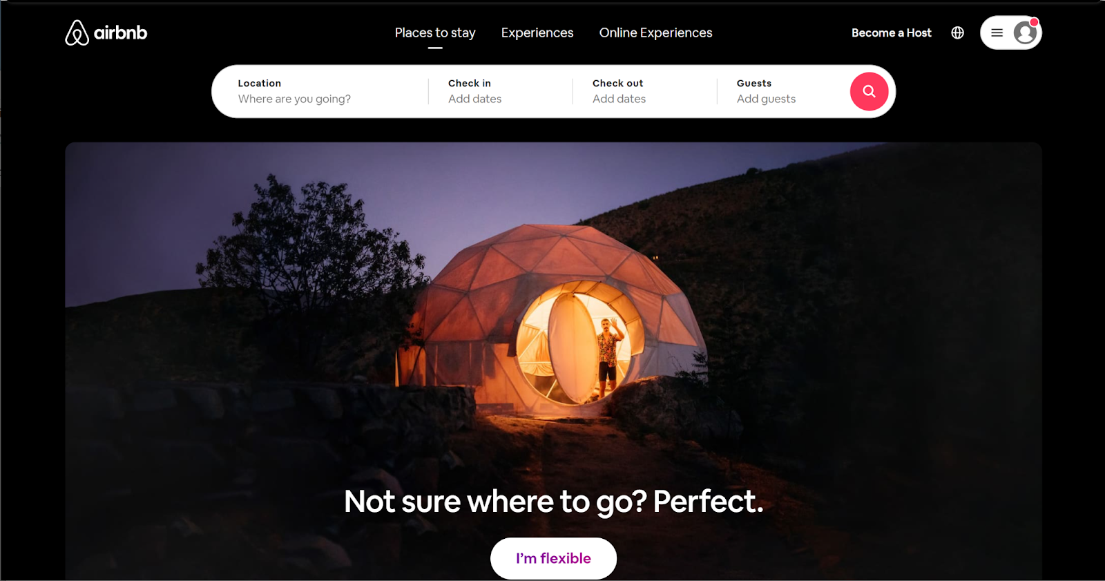In the 2021 home page, there are boxes at the top of the page to select location, dates, and number of guests. The rest of the page is taken up by a large image of a geodesic cabin with a rotating circular door. A caption says "Not sure where to go?" You can click a button below it to explore options.