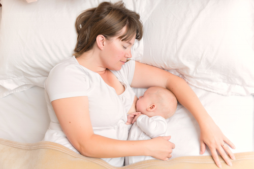 Breastfeeding mom in bed with her baby