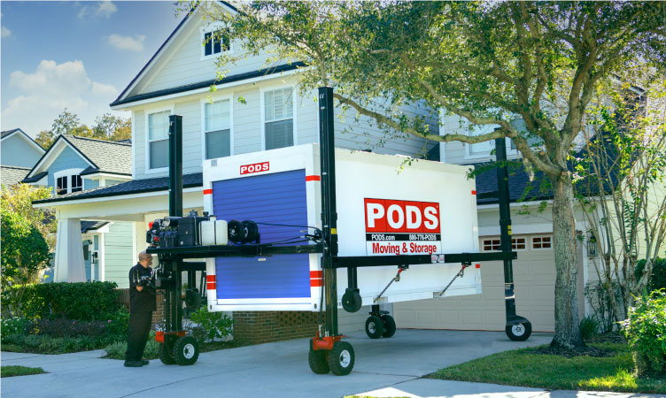 A PODS driver is using PODZILLA to place a PODS portable moving and storage container in a driveway.