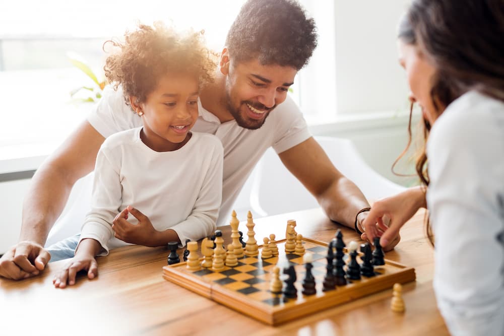 Parents playing chess with child