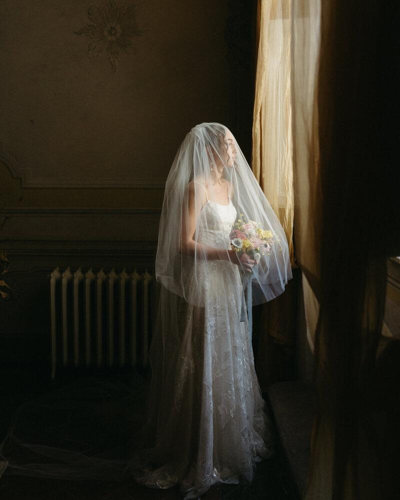 Bride looking out the window before her wedding ceremony