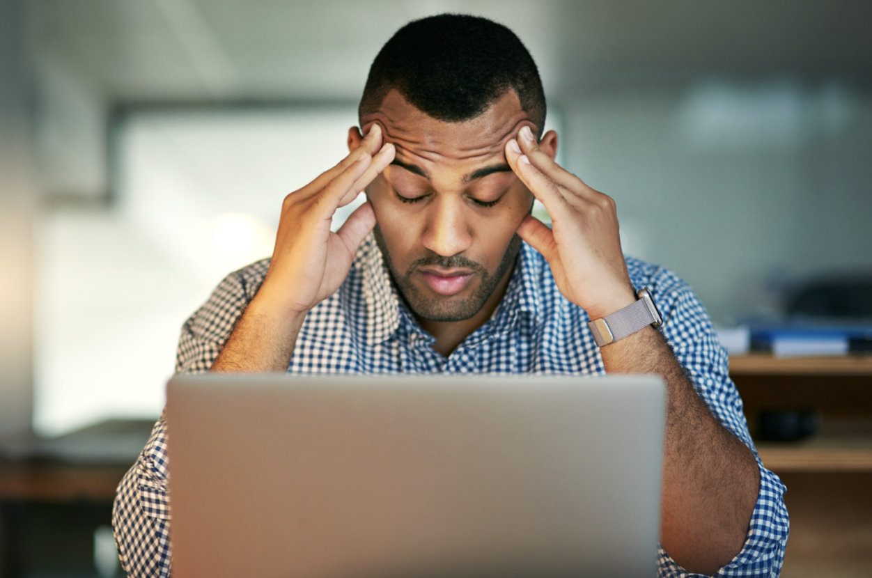A man with his head in his hands at a laptop suffers from chronic stress