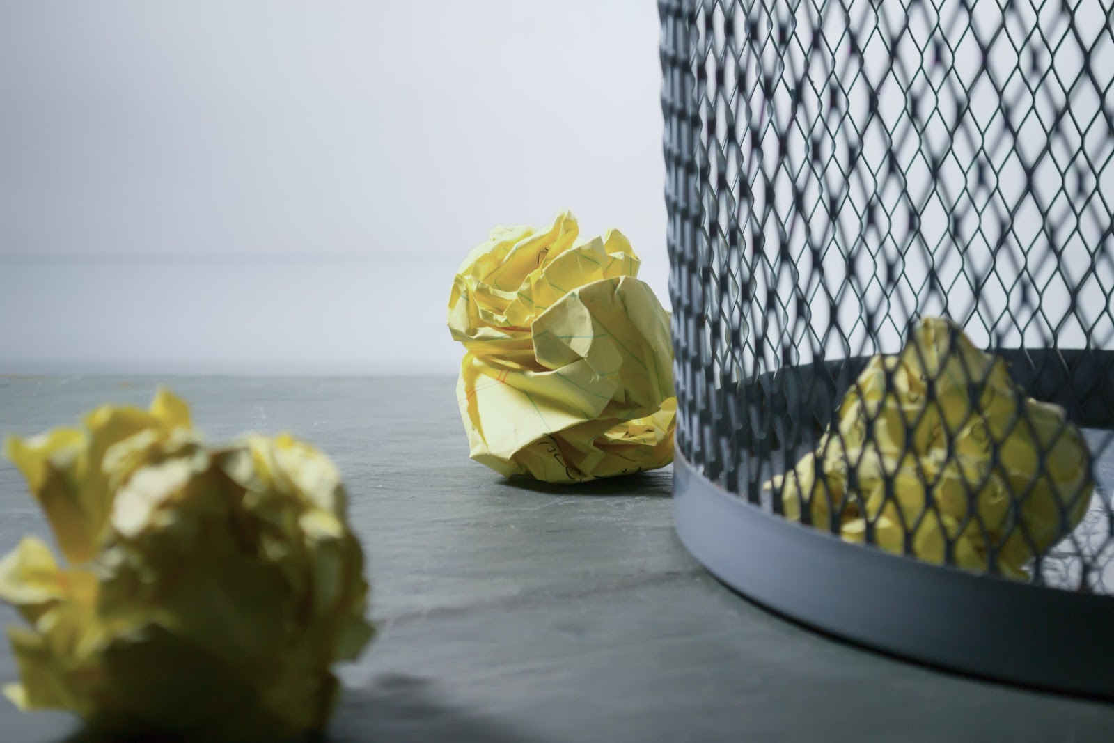 Yellow crumpled papers by and near the trash can.