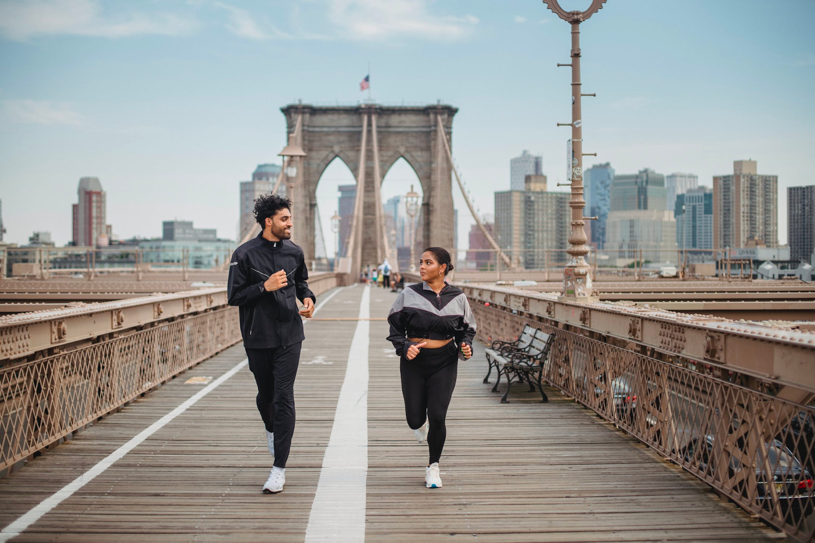 a couple running across the Brooklyn bridge