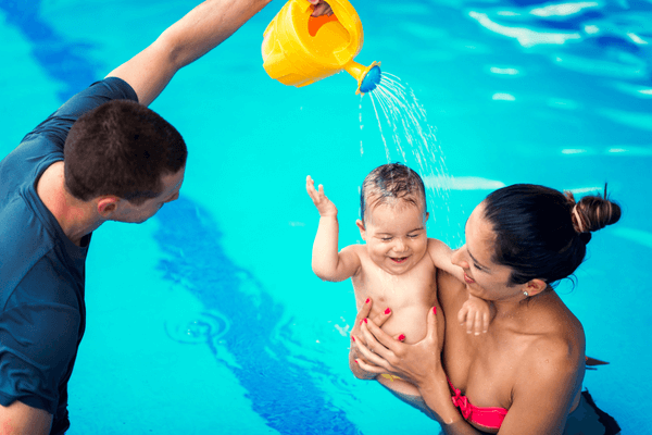 Infant swim class with instructor gently pouring water on infant's head