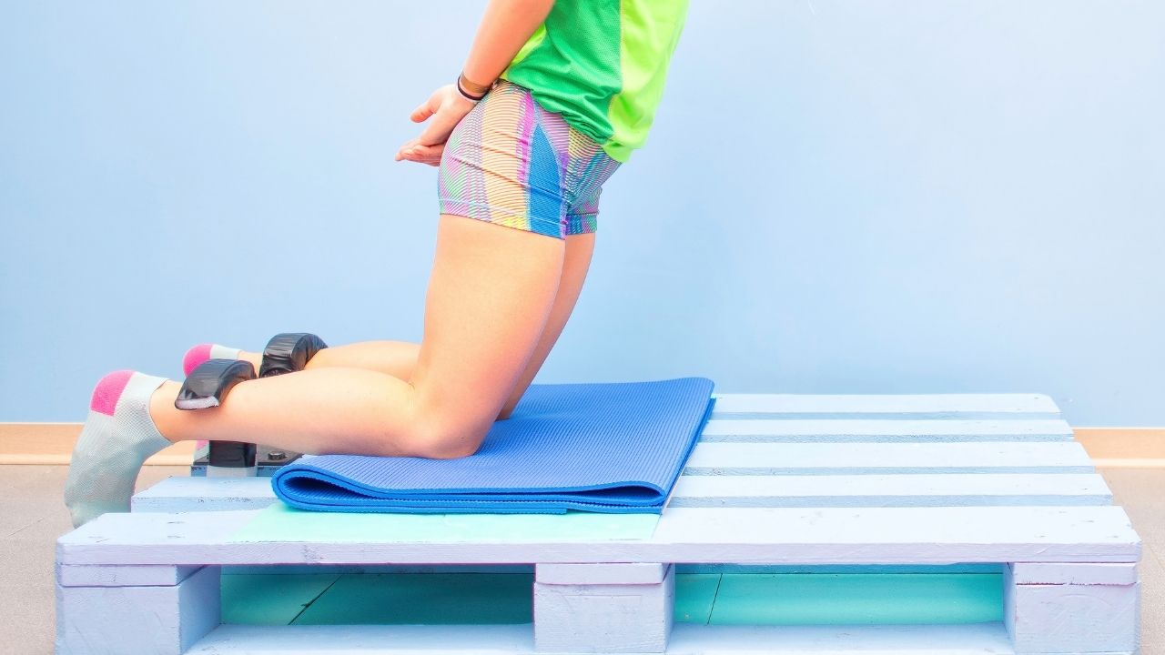 A woman performs a Nordic hamstring or Nordic curl exercise.