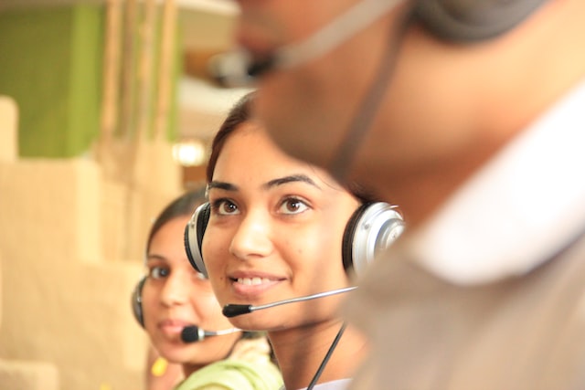 Smiling female customer support team member wearing headset, with two other team members on either side of her.