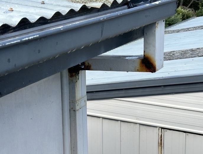 Rusty downspout caused by clogged gutters