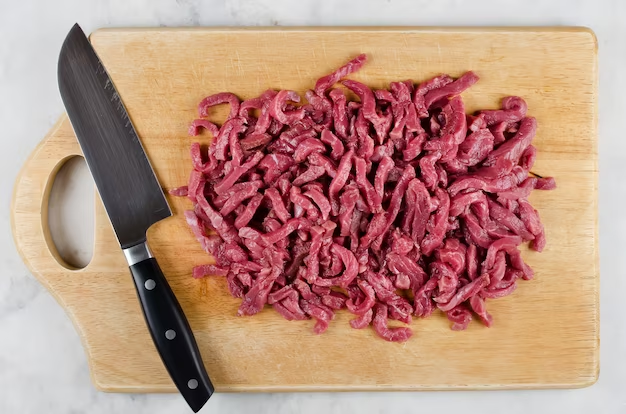 meat on a cutting board with a knife