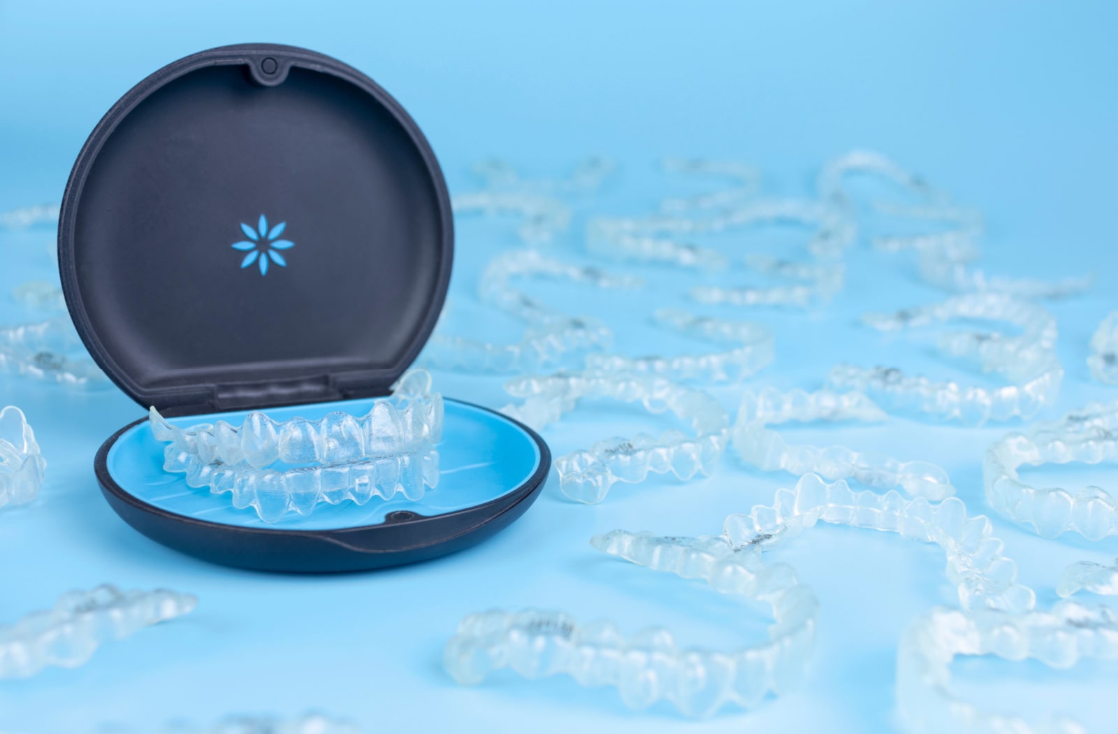 Several pairs of Invisalign 3D aligners sitting around an Invisalign branded case